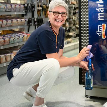 Takarító munkatárs törli át az üzletben a polcot.